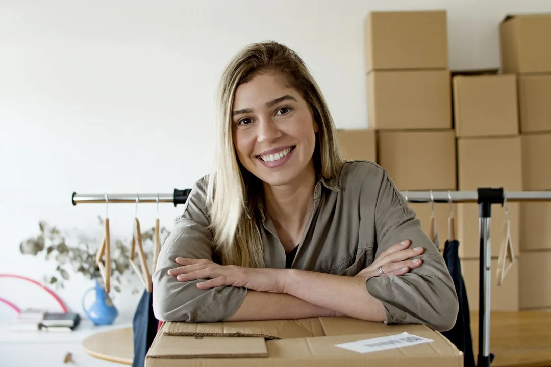 A small business owner managing her online shop with packaged orders and a clothing rail