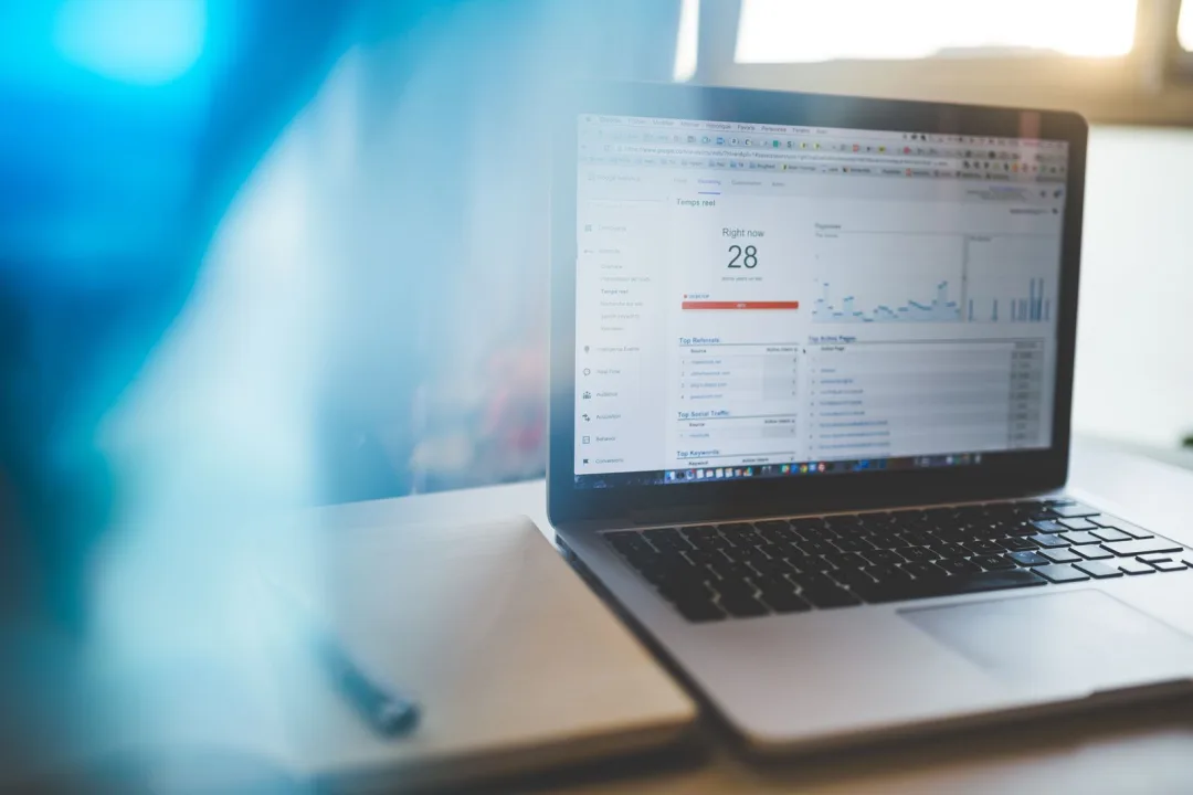 A laptop showing a Google Analytics dashboard on a desk in a modern workspace