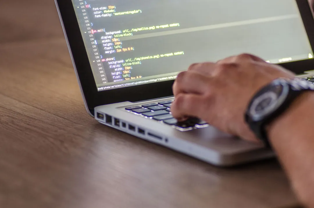 Close-up of a developer writing code on a laptop